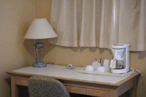 Wakaw Lodge Motel في Wakaw: طاولة عليها صانع قهوة ومصباح