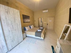 a small bedroom with a bed and a window at Fiftyfour West Boutique Living in Għarb