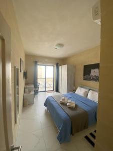 a bedroom with a blue bed and a balcony at Fiftyfour West Boutique Living in Għarb
