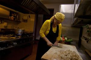 皮耶迪盧科的住宿－Complesso Agrituristico La Ciriola，一位在厨房里用切刀准备食物的女人