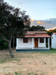 a small white house with a tree next to it at Chales Estiva Nova in Mucugê