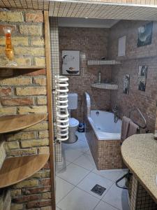 a bathroom with a brick wall and a tub at Fortuna Vendégház Erkélyes Lakosztály in Kiskunhalas +9 photos