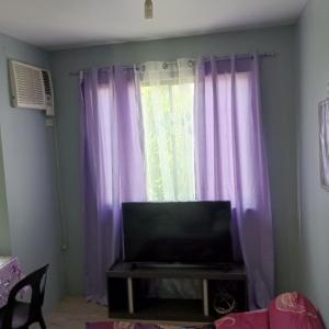 a living room with purple curtains and a television at Josephine Macatula in Santa Rosa