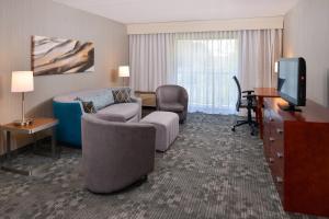 a hotel room with a bed and a desk and a television at Courtyard by Marriott Charlotte Gastonia in Gastonia
