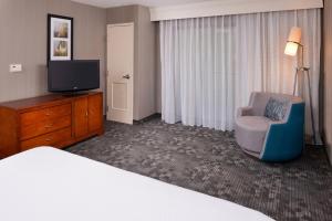 a hotel room with a bed and a chair and a television at Courtyard by Marriott Charlotte Gastonia in Gastonia +17 photos