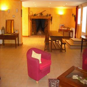 ein Wohnzimmer mit einem roten Stuhl und einem Kamin in der Unterkunft Gîte de Pailherols in Pailherols