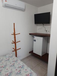 a room with a bed and a tv and a tv stand at Hotel Pousada Guaratuba in Guaratuba