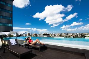a woman sitting on a chair next to a swimming pool at JW Marriott Hotel Santo Domingo in Santo Domingo