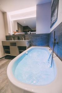 a bath tub filled with blue water in a bathroom at LIVALPIN 2Enjoy - with private Sauna in Garmisch-Partenkirchen +32 photos