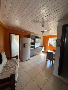 - une cuisine avec des murs orange et un réfrigérateur blanc dans l'établissement Recanto do Sul - Campeche, à Florianópolis