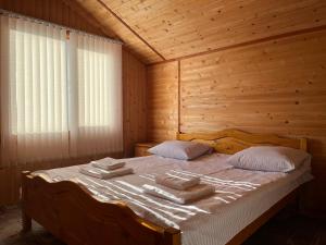 Una cama en una habitación de madera con toallas. en Котедж Краєвид, en Yablunytsya