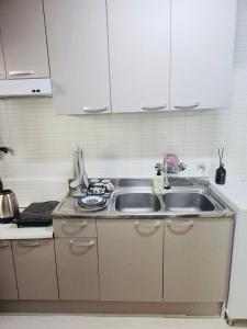 Una cocina con gabinetes blancos y un fregadero. en Cozy guesthouse, 10 minutes from SNU Entrance Station, accommodation in Sharosu-gil, OTT, Nespresso machine, within 25 minutes by subway to Hongdae, Gangnam, Seongsu, Gwanaksan, up to 5 people, en Seúl 29 fotos más