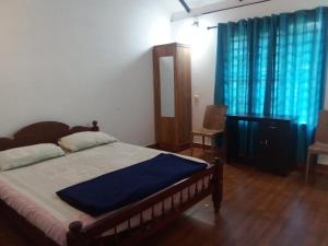 a bedroom with a bed with blue sheets and blue curtains at River View Guest Rooms in Vythiri