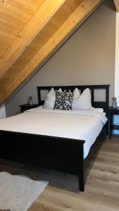 a bedroom with a black bed with white sheets and pillows at Ferienapartment bavarian living in Moosinning