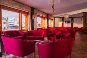 a waiting room with red chairs and a mountain at Hotel Galassia in Prato Nevoso