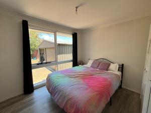 a bedroom with a colorful bed and a large window at The Nest in Bidwill