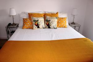 Una cama con almohadas de color naranja y amarillo. en Tapada da Rabela - Reserva Natural, en Marvão