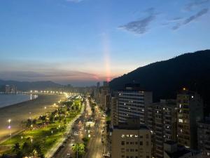 サン・ビセンテにあるApto 18 - Pé na areia, Santosの夜のビーチ付きの市街の景色 +3枚の写真