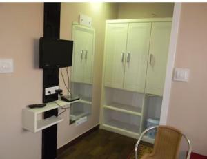 a small room with a tv and some cabinets at Hotel Mothimahal in Trichūr