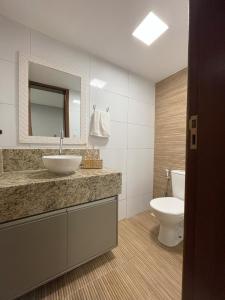 a bathroom with a sink and a toilet and a mirror at Casa em Vilas 70m da Praia in Lauro de Freitas