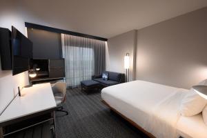 a hotel room with a bed and a chair at Courtyard by Marriott Charlotte Waverly in Charlotte