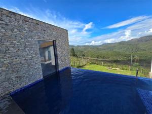 a house with a swimming pool next to a stone building at La Villa Novas Pousada in Lavras Novas