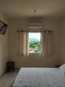 a bedroom with a bed and a window at Chalés Xibayka Ilhabela in Ilhabela