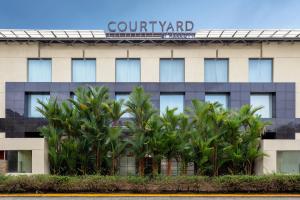 a building with palm trees in front of it at Courtyard by Marriott Kochi Airport in Nedumbassery