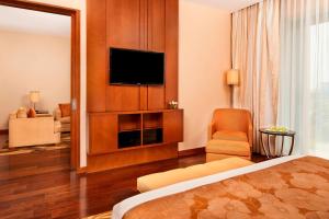 a hotel room with a bed and a flat screen tv at Courtyard by Marriott Kochi Airport in Nedumbassery
