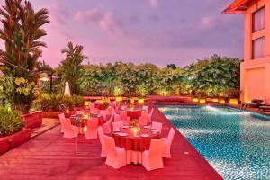 a patio with tables and chairs next to a swimming pool at Courtyard by Marriott Kochi Airport in Nedumbassery