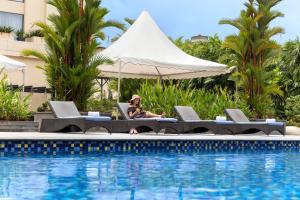 a woman sitting in a chair next to a swimming pool at Courtyard by Marriott Kochi Airport in Nedumbassery