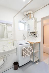 a white bathroom with a sink and a washing machine at Niseko Yu Villa B in Niseko