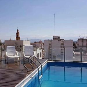 a balcony with two chairs and a swimming pool on a building at Departamento Caseros Centro in Salta