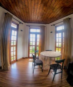a dining room with a table and chairs and windows at Hotel Grand Sun Inn in Nuwara Eliya