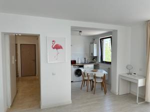 a white kitchen with a table and a pink bird painting on the wall at AMADEUS IASI in Iaşi
