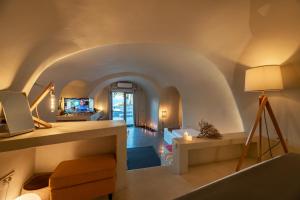 a living room with an archway with a couch and a tv at 270 Oias View in Oia