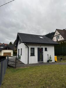 ein weißes Haus mit einem schwarzen Dach und einem Hof in der Unterkunft Domek na Kępce in Szczyrk