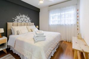 a bedroom with a large white bed with a window at Mi Lugar en Rosario - Depto céntrico VIP con cochera cubierta in Rosario