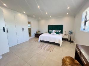 een slaapkamer met een bed met een groen hoofdeinde bij Villa Lamsyh- your second home in Kaapstad +61 foto's