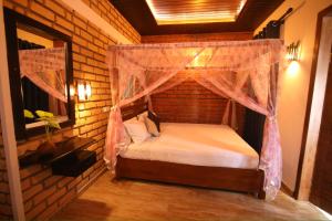 - une chambre avec un lit à baldaquin dans un mur en briques dans l'établissement Rovenluck Eco Cabana, à Weligama
