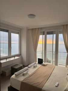 a bedroom with a large bed with large windows at Deluxe Apartments Shengjin in Shëngjin