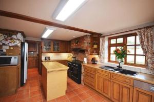 a large kitchen with wooden cabinets and a sink at Nuthooks House in Cadnam