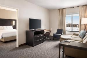a hotel room with a bed and a flat screen tv at Residence Inn by Marriott Des Moines Ankeny in Ankeny