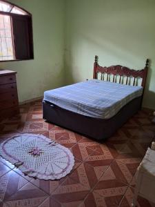 a bedroom with a bed and a rug on the floor at Casa com pisicna in Mongaguá in Mongaguá