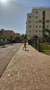 una persona seduta su una panchina in mezzo a una strada di Appartement Caraïbe a Rufisque