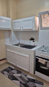 una cucina con mobili bianchi, un lavello e una stufa di Appartement Caraïbe a Rufisque