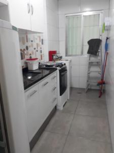 a kitchen with a stove and a white refrigerator at Apartamento São Vicente in São Vicente