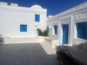 a white building with blue windows and a patio at L'autre Dar Rita in Houmt Souk