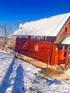 a log cabin with ice on the roof in the snow at Etno dom Bubalo in Čajetina