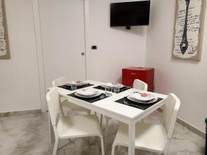 a white dining room table with white chairs and a television at la casa di patta a spaccanapoli in Naples